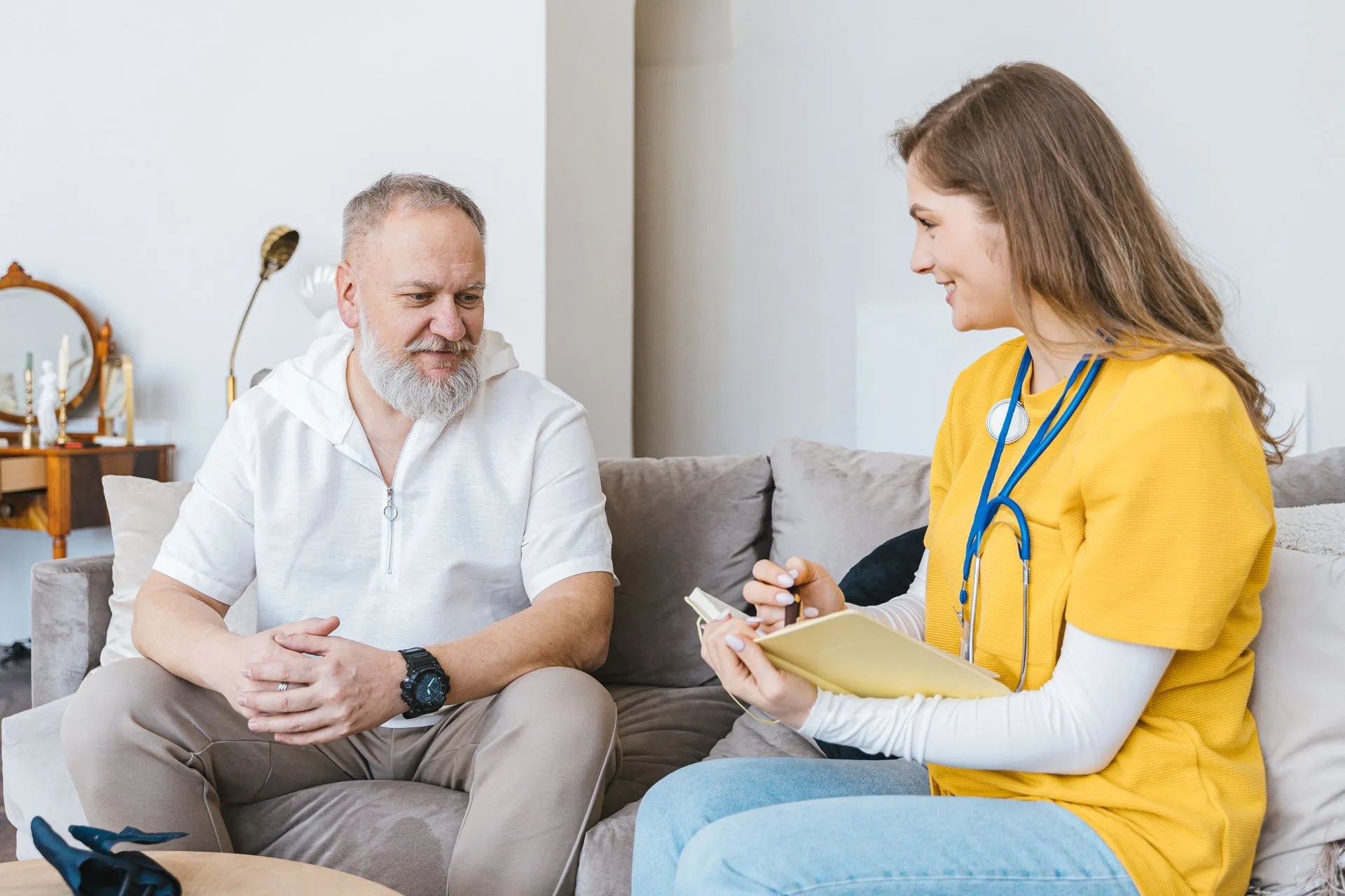 A home health nurse talking with a smiling senior patient at home